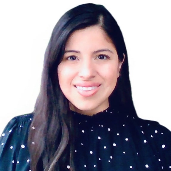 Photo of female is a black blouse with white polkadots. She is smiling with long brown straight hair. 