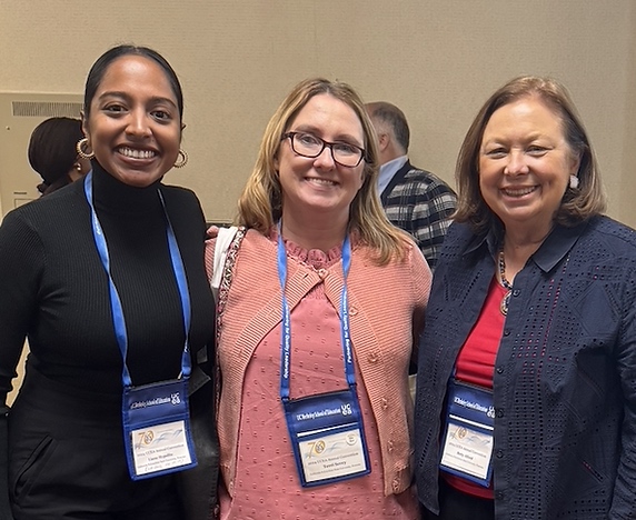 Three faculty smiling and standing. 