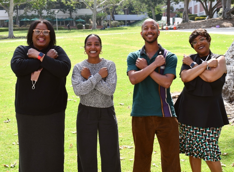 Students posing for a photo. There is a grass field behind them. 