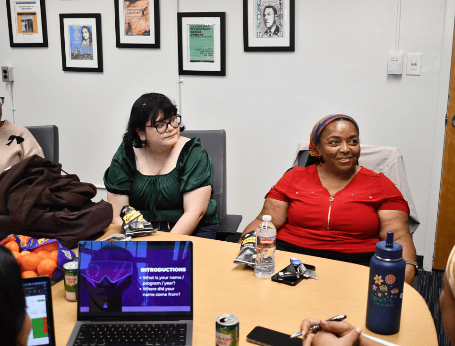 Two female students are seated and listening to a presentation. 