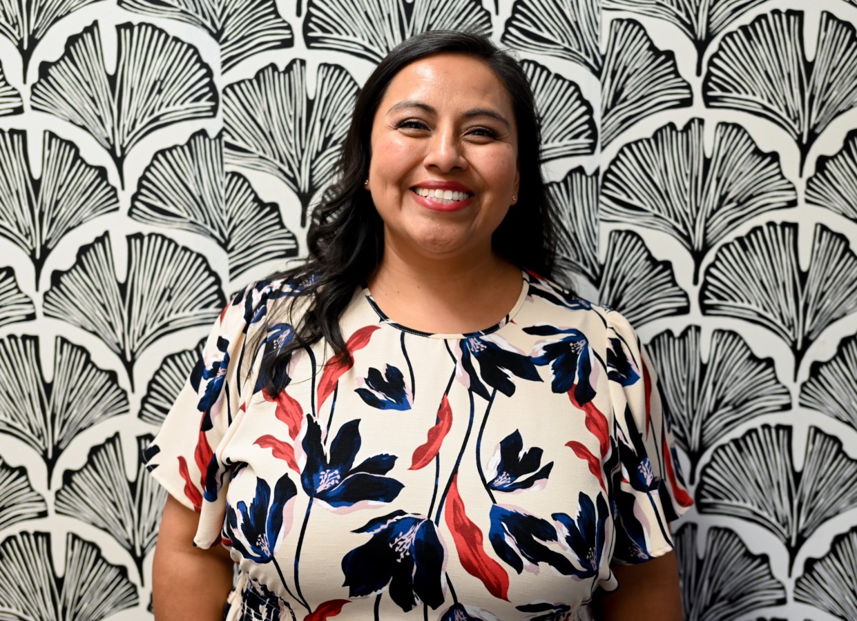 Female wearing floral top behind a black and white floral design background. 