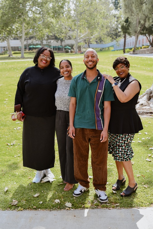 Group of students holding up their hands standing and smiling for a group photo. 
