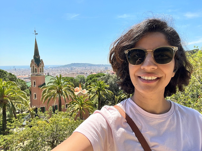 Selfie of Purdeep smiling with jungle and steepled building