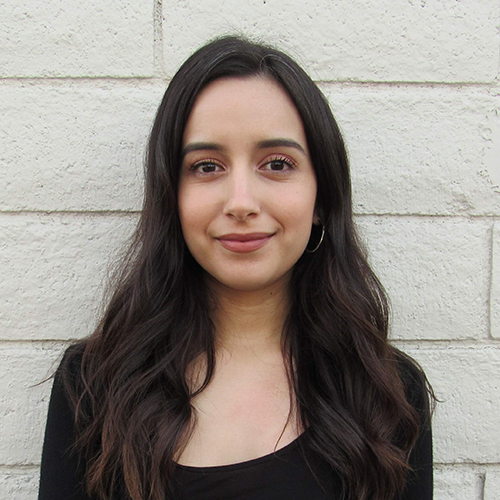 Headshot of Elizabeth against a white painted cinder block wall