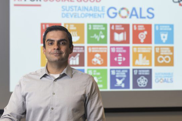 Dr. Gabe Granco posing in front of projector screen