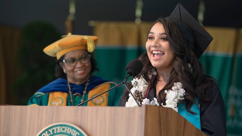 A Communication Department graduate with President Coley in the back