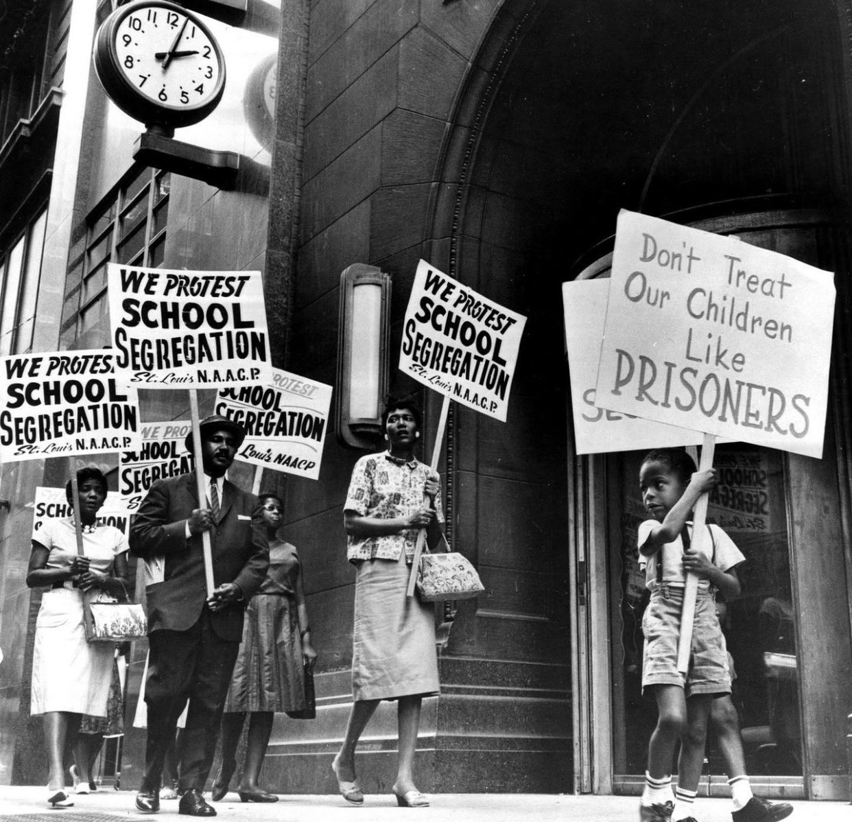 A black and white photograph of protesters carrying placards protesting segregation