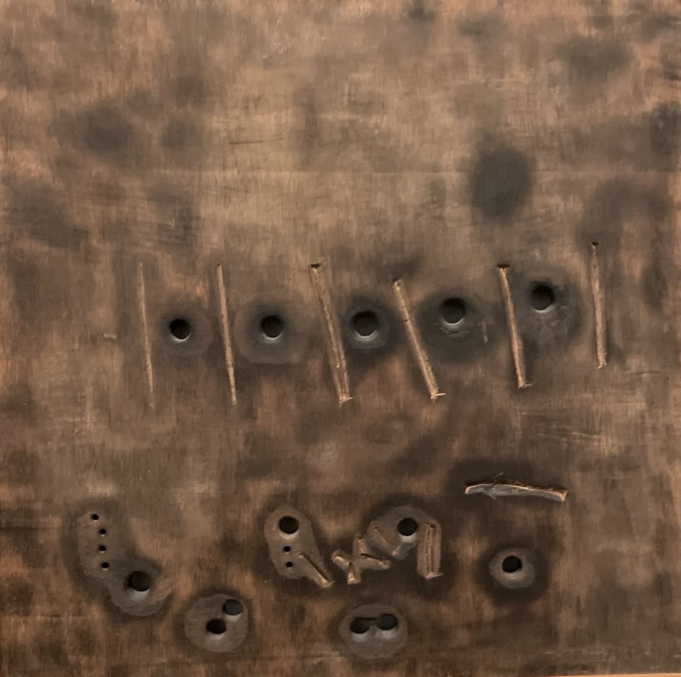 Photograph of an artwork depicting a wall riddled with bullets