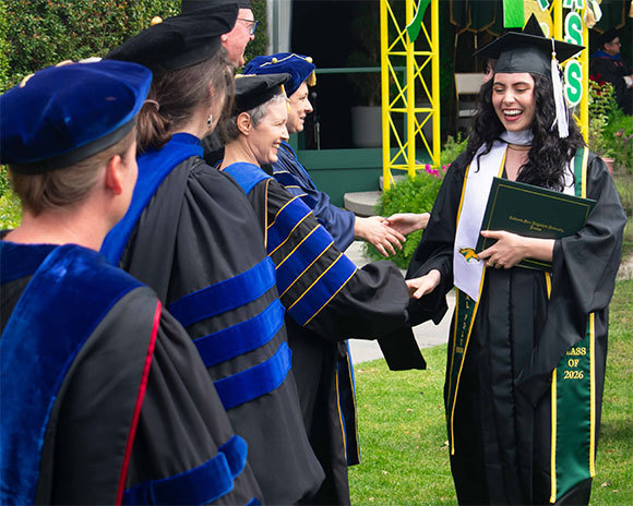 Happy Graduate shaking hands with professors at Commencement Ceremony