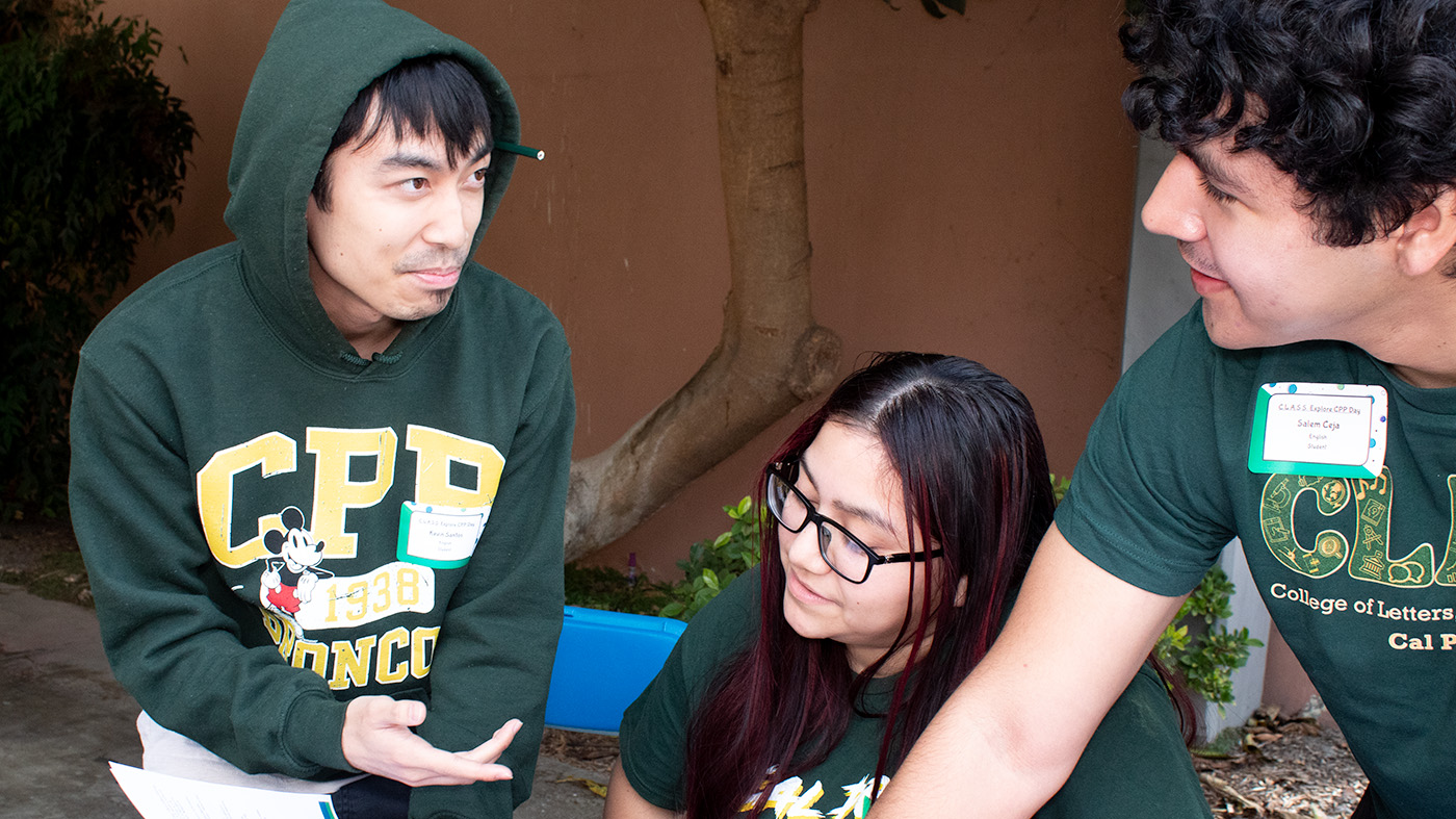 3 students with Bronco branded clothing interacting.