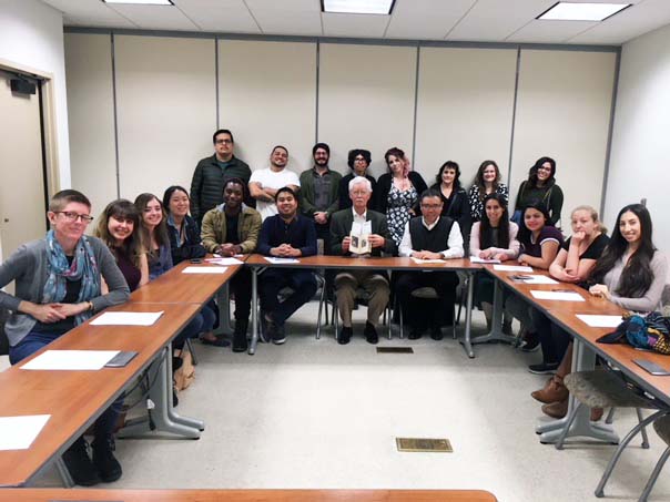 20 people sit around a table in a meeting room and smile for the camera: 18 students, Dr. Hall, and Steve Tabor, Curator of Rare Books at the Huntington Library