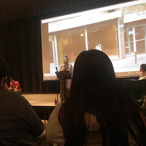 Artist Josefina Báez gives a reading in front of a projected video during the event