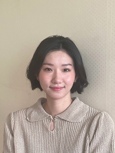 Headshot of Asian CPP alumna with short black hair and brown eyes, wearing a tan blouse against a light background