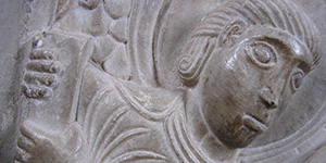 stone relief sculpture of a person holding a book