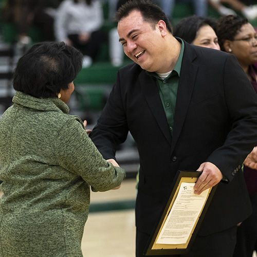 Camacho shakes hands with President Coley after receiving his plaque