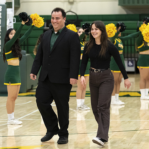 Camacho and Brown smile as they walk through a cheer line