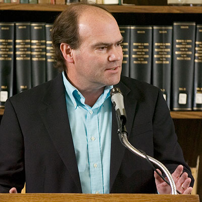 a speaker delivering a speech in front of a bookshelf