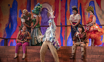 Students acting a dramatic play on stage, featuring elaborate costumes and stage design