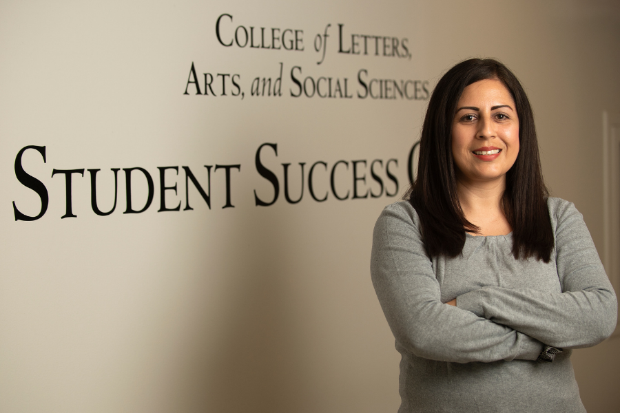 Maria crossing her arms in front of the student success center signage