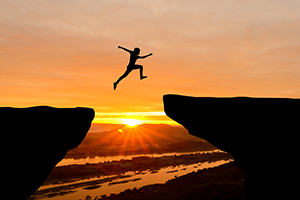 silouette of person jumping cliffs