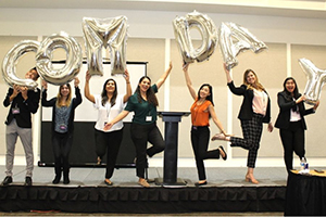 Students holding balloons that spell Com Day