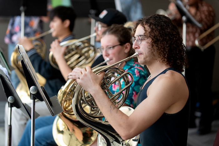 Students performing on French horns during a Cal Poly Pomona brass ensemble rehearsal or concert.