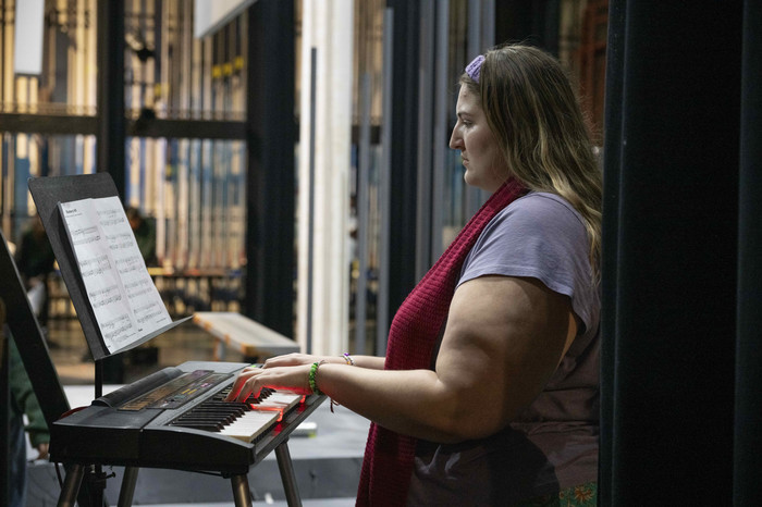 Student playing keyboard backstage, focused on sheet music during a rehearsal or performance at Cal Poly Pomona.