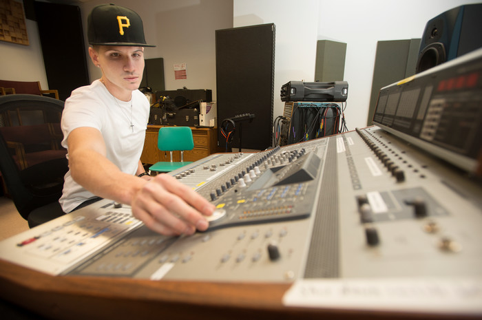 Student working at an audio mixing console in a Cal Poly Pomona music production lab.
