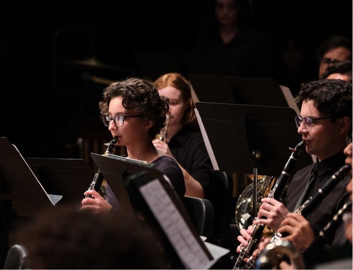 Students performing on woodwind instruments during a concert with the Cal Poly Pomona band ensemble.