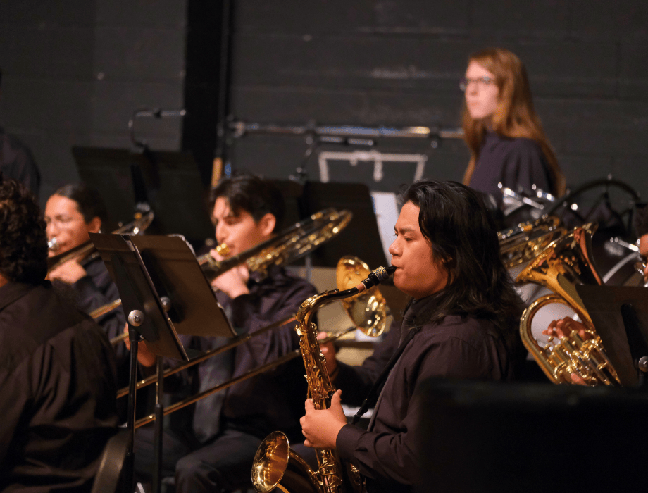 Student musicians perform with the Cal Poly Pomona Bands, playing saxophones and brass instruments during a concert.