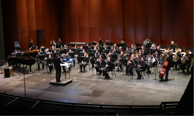 The Cal Poly Pomona Bands perform on stage with a full ensemble of musicians led by a conductor.