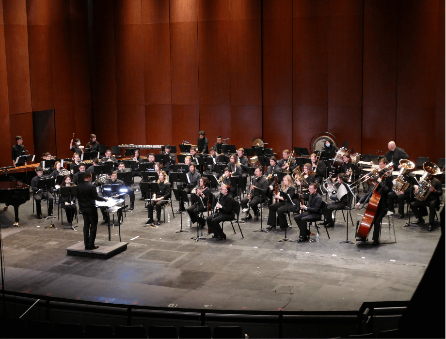 The Cal Poly Pomona Bands perform on stage with a full ensemble of musicians led by a conductor.
