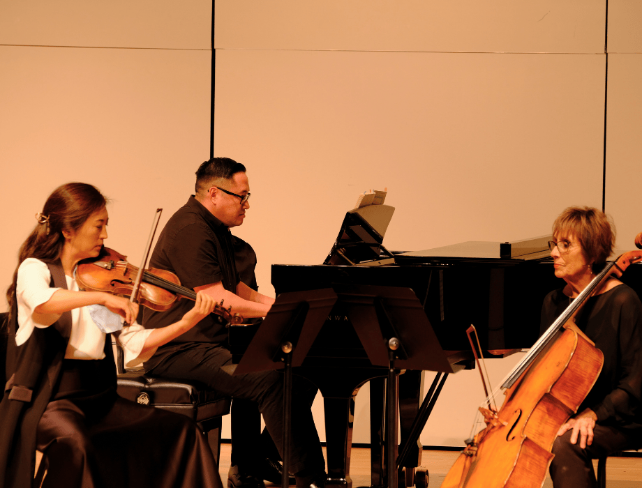 The Kellogg Piano Trio performs on stage, featuring musicians on violin, piano, and cello during a concert.