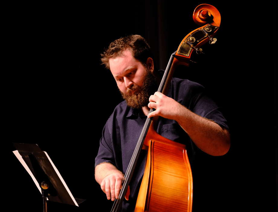 A musician performs on stage playing an upright bass during an orchestra concert.