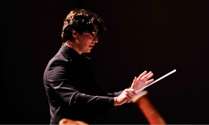 Christian Solis Alvarado conducting on stage during a performance.