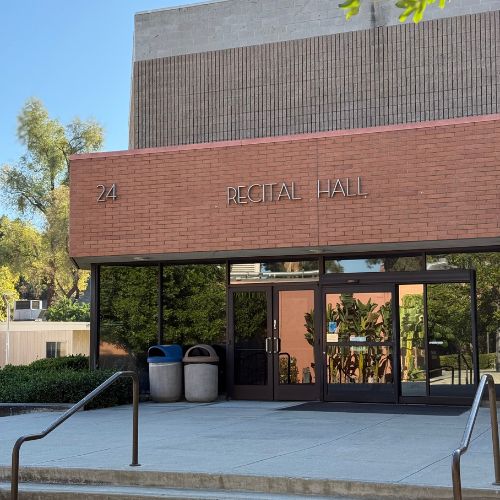 Exterior of Cal Poly Pomona’s Recital Hall, building 24, with glass doors and surrounding greenery.