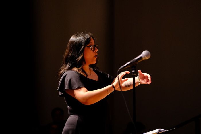 CPP music education student conducts a choir during a live performance with a microphone in front.
