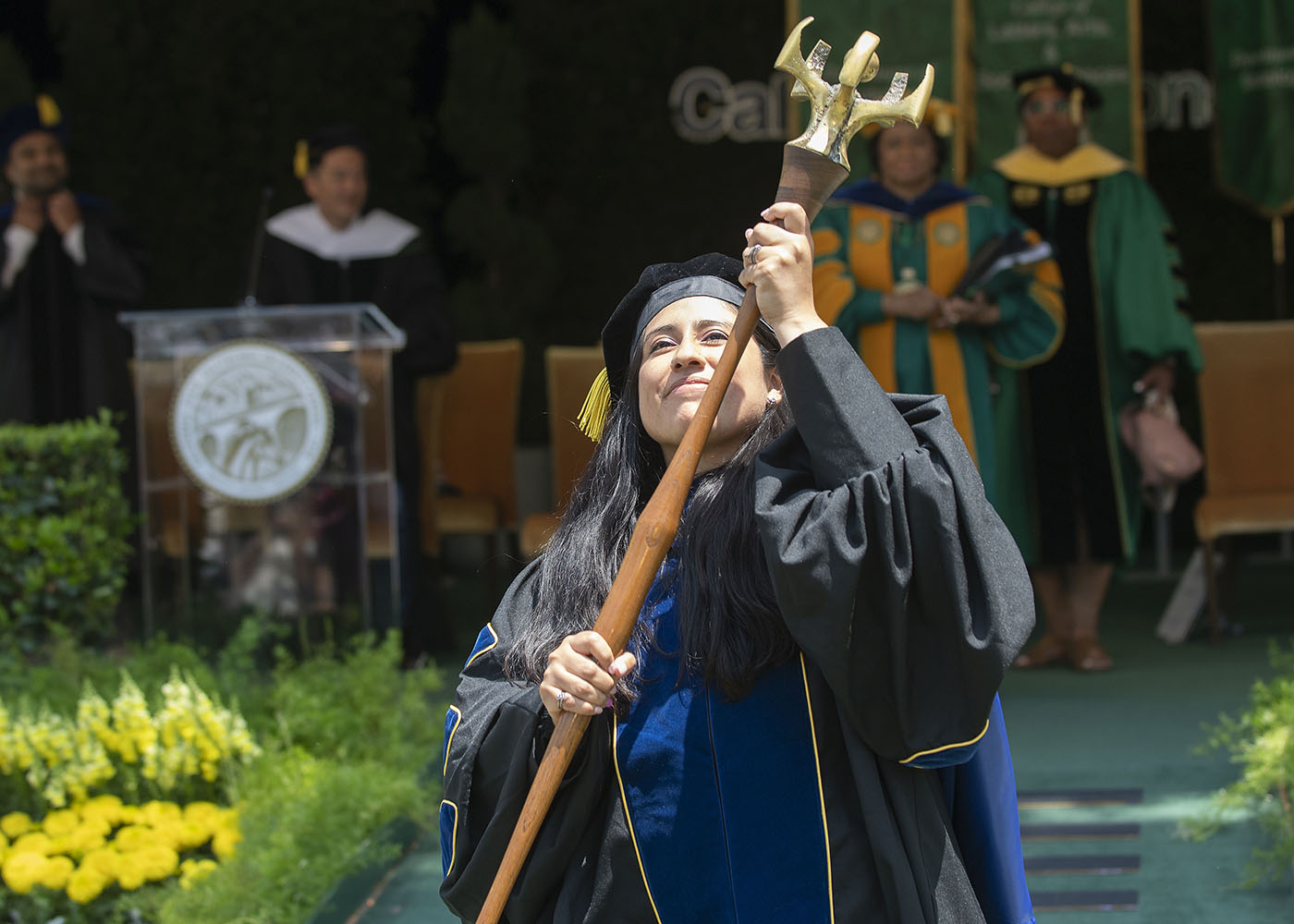 Faculty holding a ceremonial mace during Cal Poly Pomona commencement