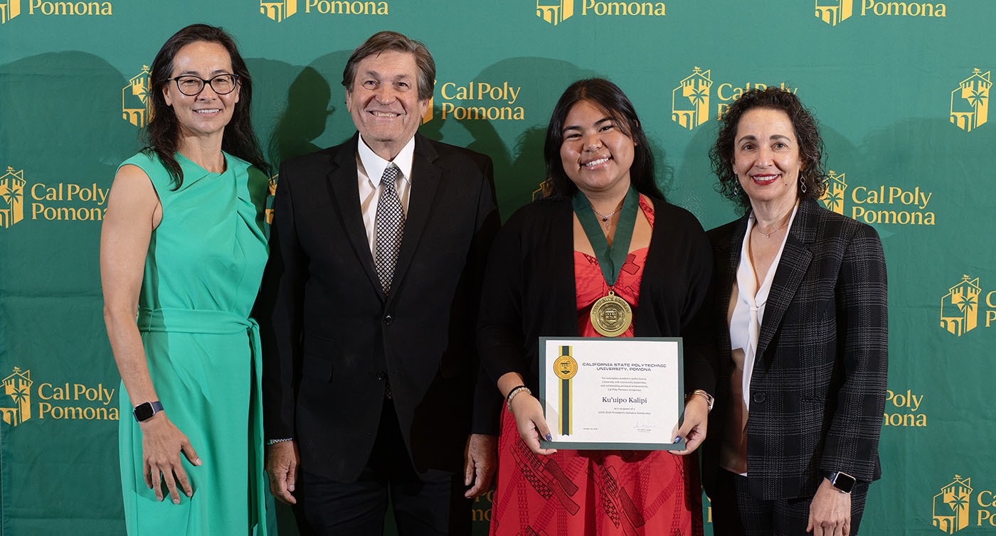 A student holding a scholarship award with other faculty members at CPP