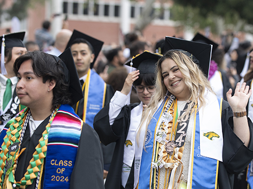 -- Insert Alt Text -- Four faculty members in academic regalia pose together at commencement.