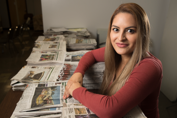 Student on a table with lots of newspapers