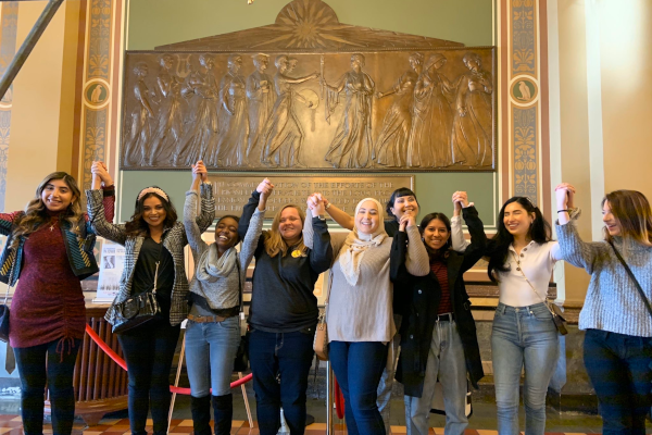 happy female students holding hands in a group