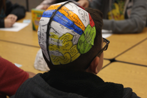 student wearing colorful head piece with labelled areas of the brain