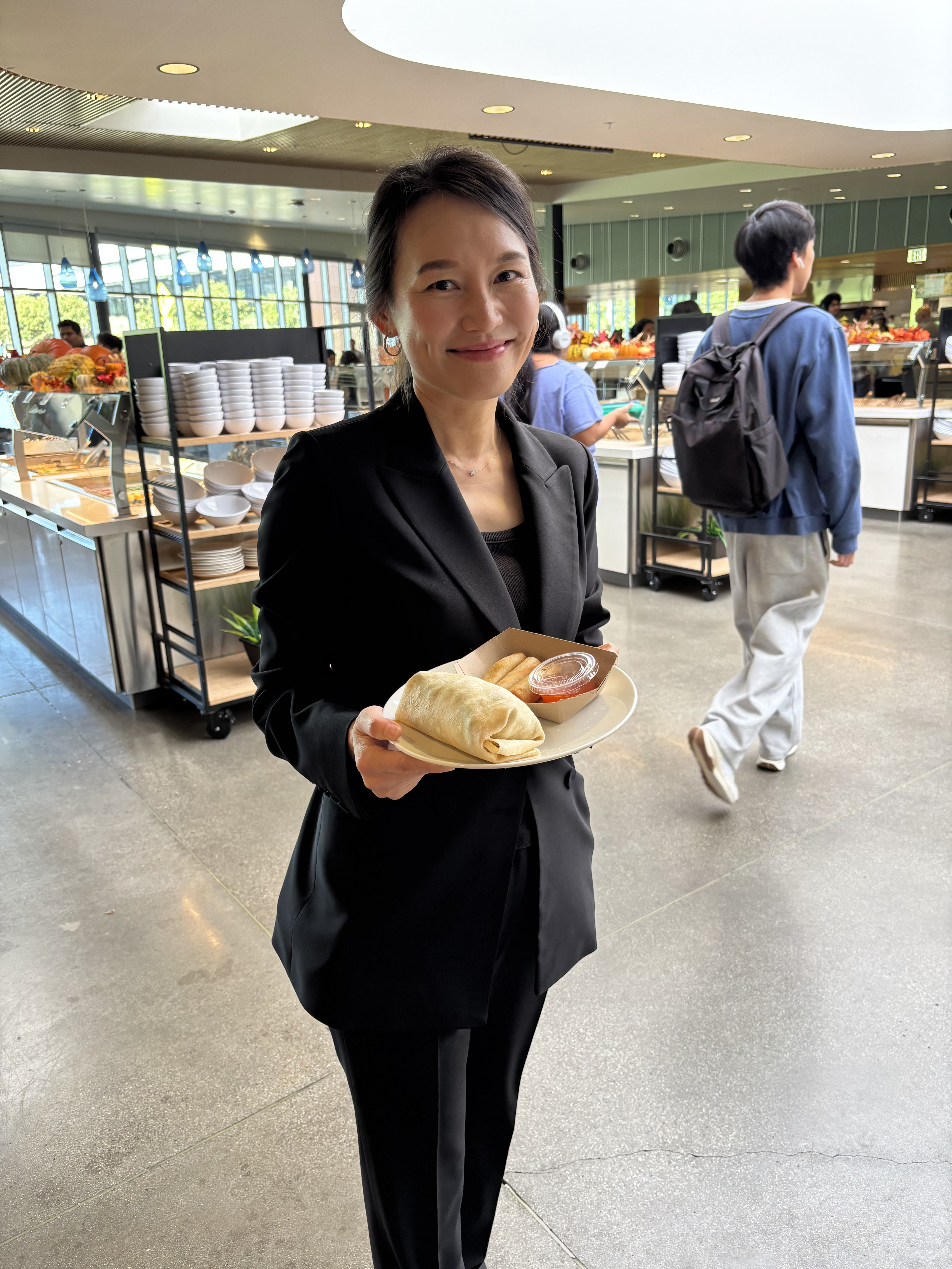 Dr. Kelly Min holding a plate containing Passport Wraps food