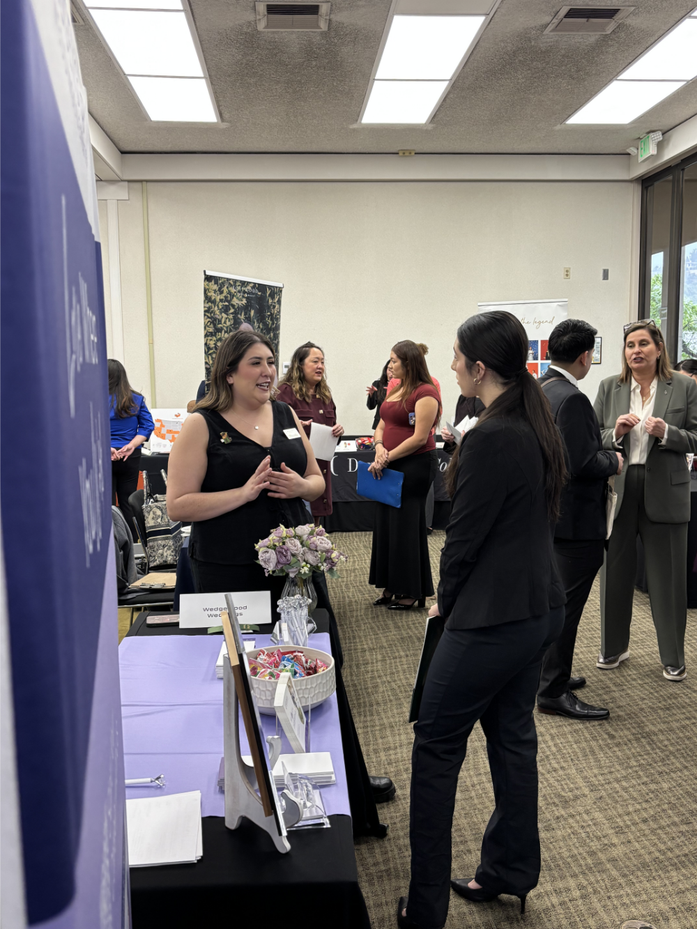 Students inside the hospitality expo talking at tables.