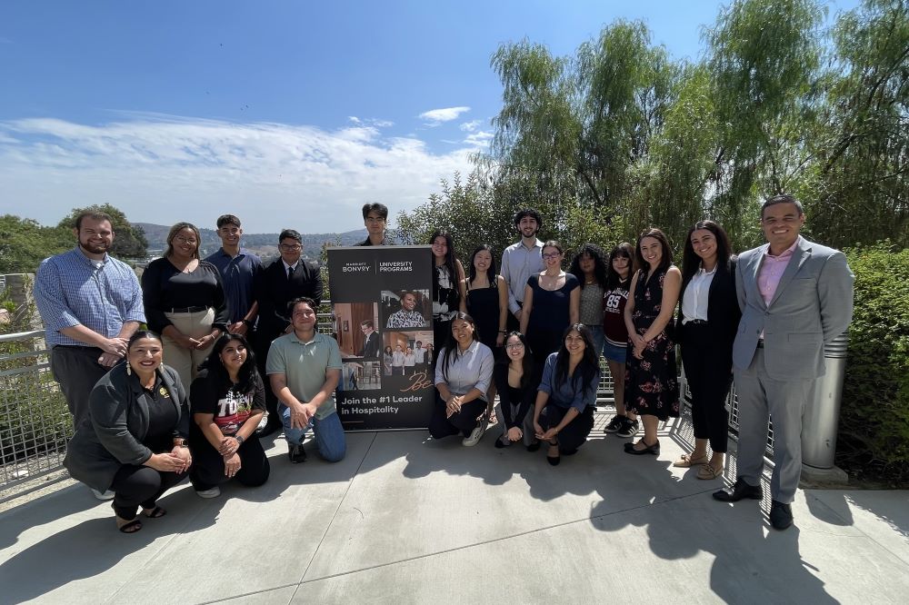 A group of people gathered around the Marriott Bonvoy advertising signage outside Building 80.