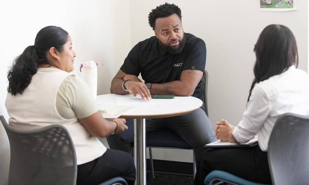 Students at a table in Building 80 speaking with a Hyatt recruiter during a scheduled meeting. 