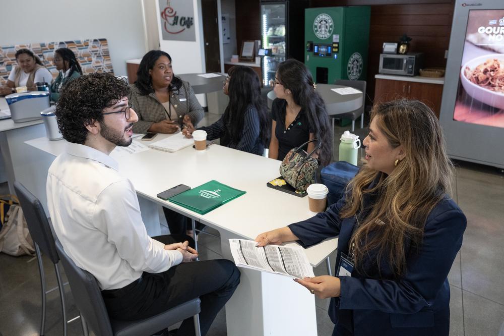 A table of students and Hilton recruiters talk over coffee in H-Cafe.