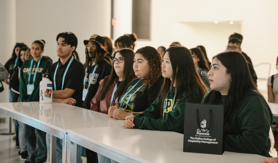 Students on field trip listening at counter wearing lanyards during SoFi Stadium tour