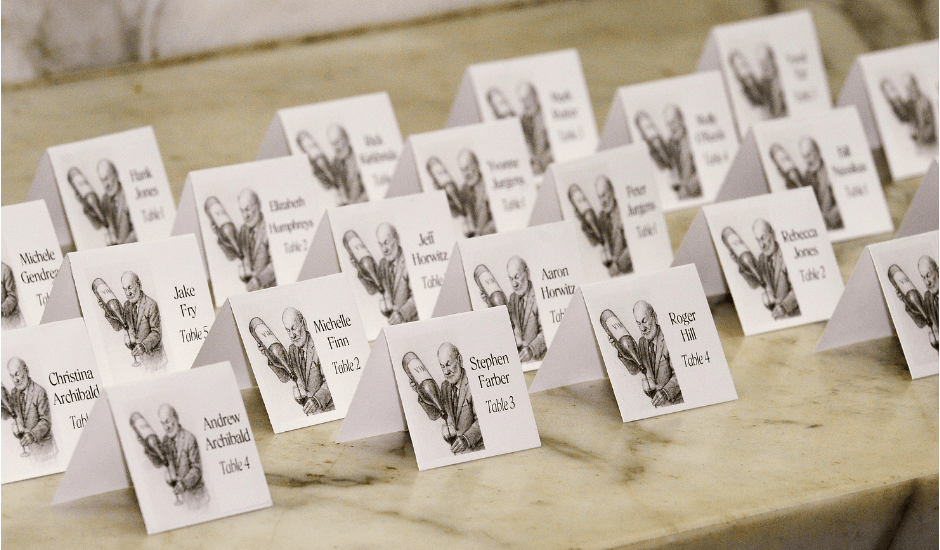 Rows of white place cards with guest names arranged on a marble table for event seating.